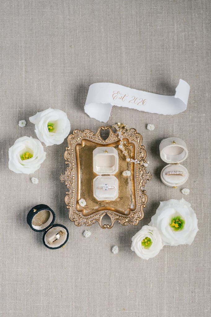 A wedding flat lay of wedding rings and flowers. 