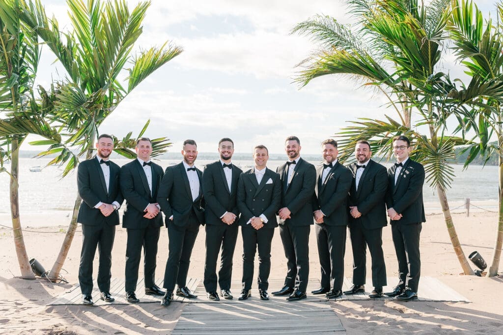 The groomsmen stand on the beach at the Anthony's Ocean View wedding. 