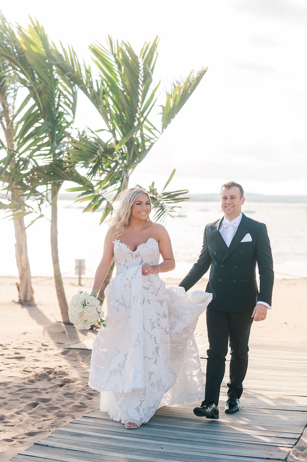Jacquie and Thomas walk alongside eachother on the beach outside of Anthony's Ocean View.