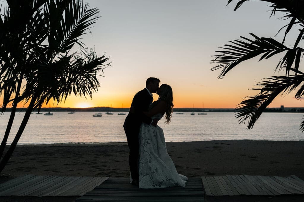 Jacquie and Thomas kiss under the sunset at Anthony's Ocean View. 