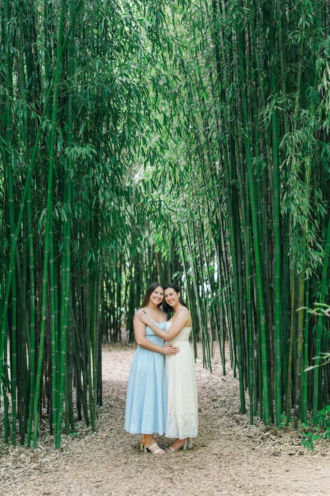 Kayla and Shannon face each other and smile under the bamboo shoots at Blithewold for their Bristol, RI engagement session