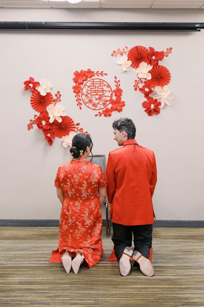 The bride and groom smile at one another as they kneel together