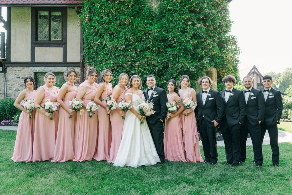 The full bridal party smiles as they stand in front of Saint Clements Castle 