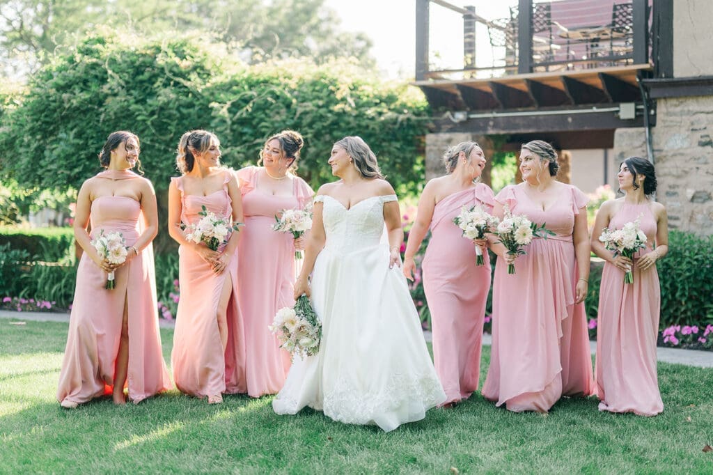 Sophie and her bridesmaids walk in front of the rose bushes