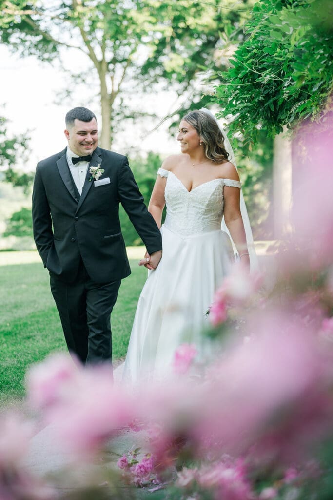 Sophie and john walk along the rose bushes at their Saint Clements Castle Wedding