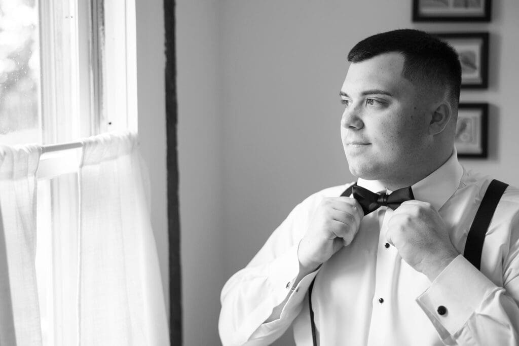 John, the groom, adjusting his bowtie on his wedding day