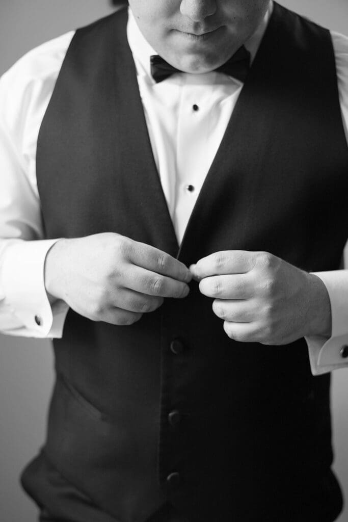 A groom adjusting buttons on his jacket
