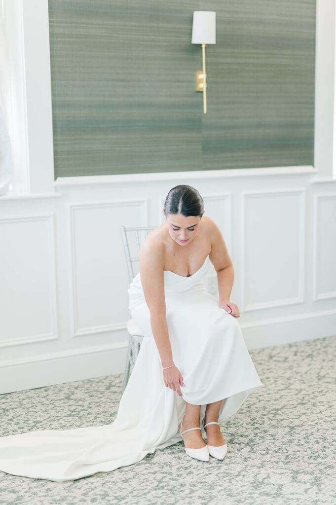 Amy leans over and puts on her wedding shoes. 