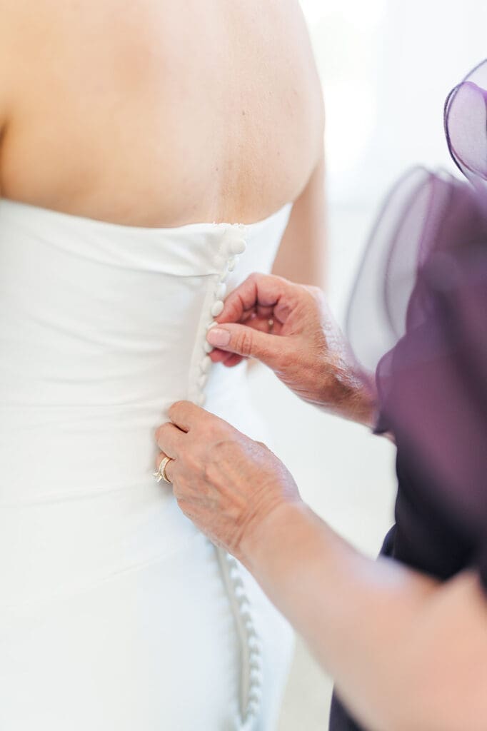 Amy's mom buttons up her wedding dress. 