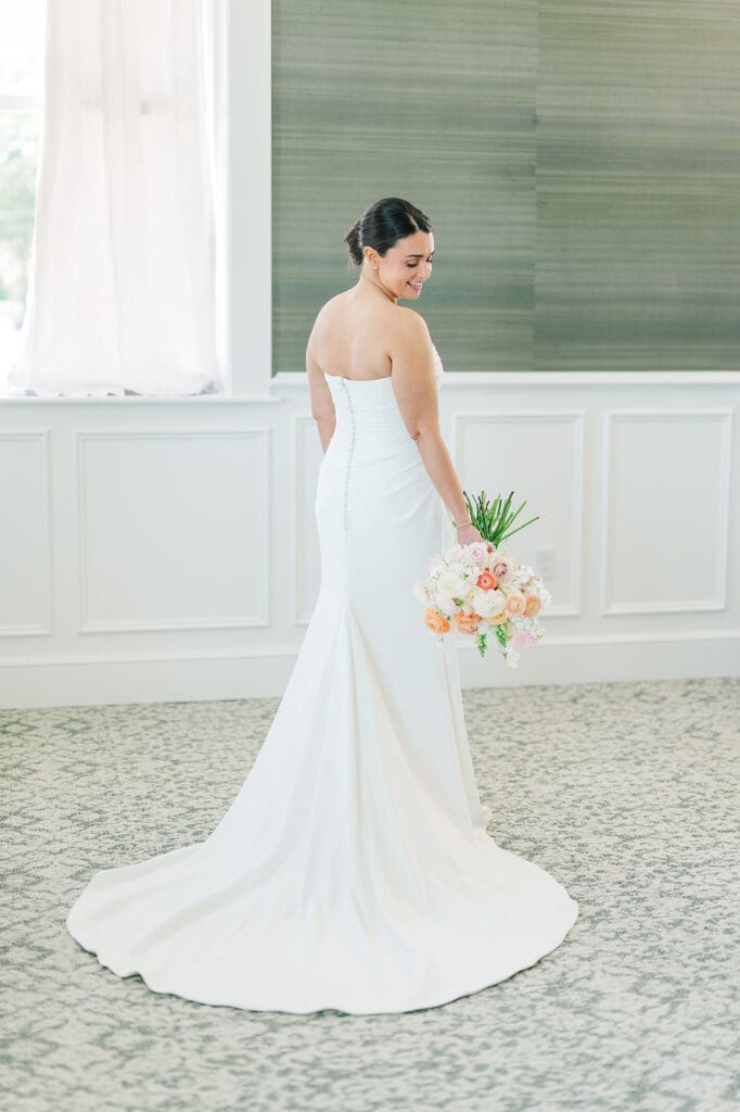 Amy looks over her shoulder while holding her bouquet. 