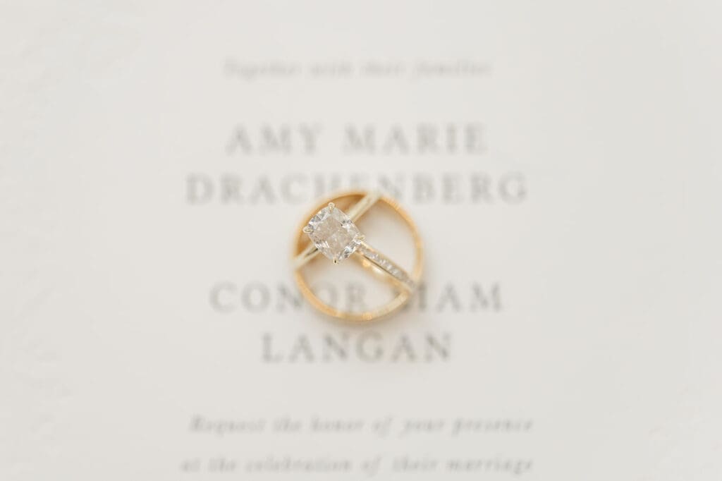 Three wedding rings on a wedding invitation for Amy and Conor. 