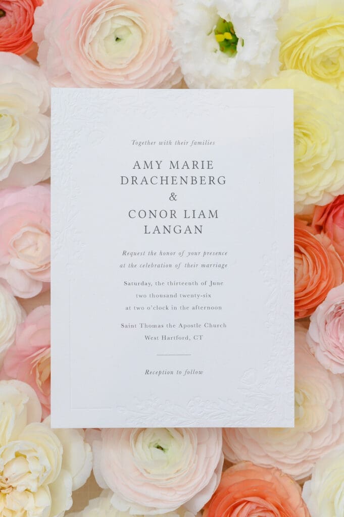A wedding invitation on top of florals. 