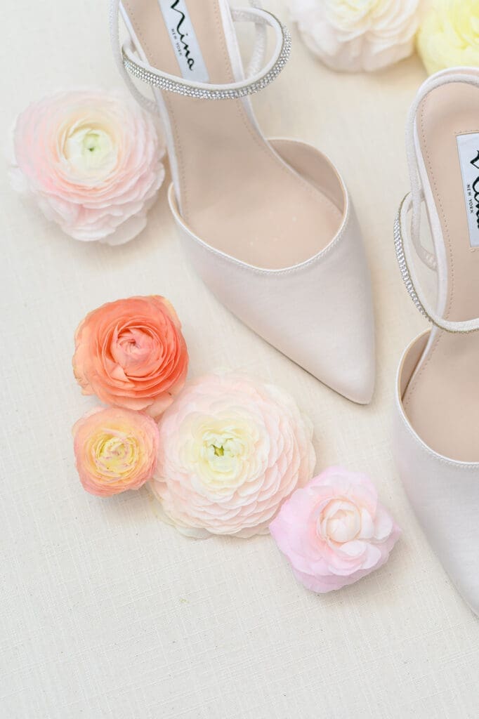 Nina shoes on a flat lay mat next to colorful florals. 