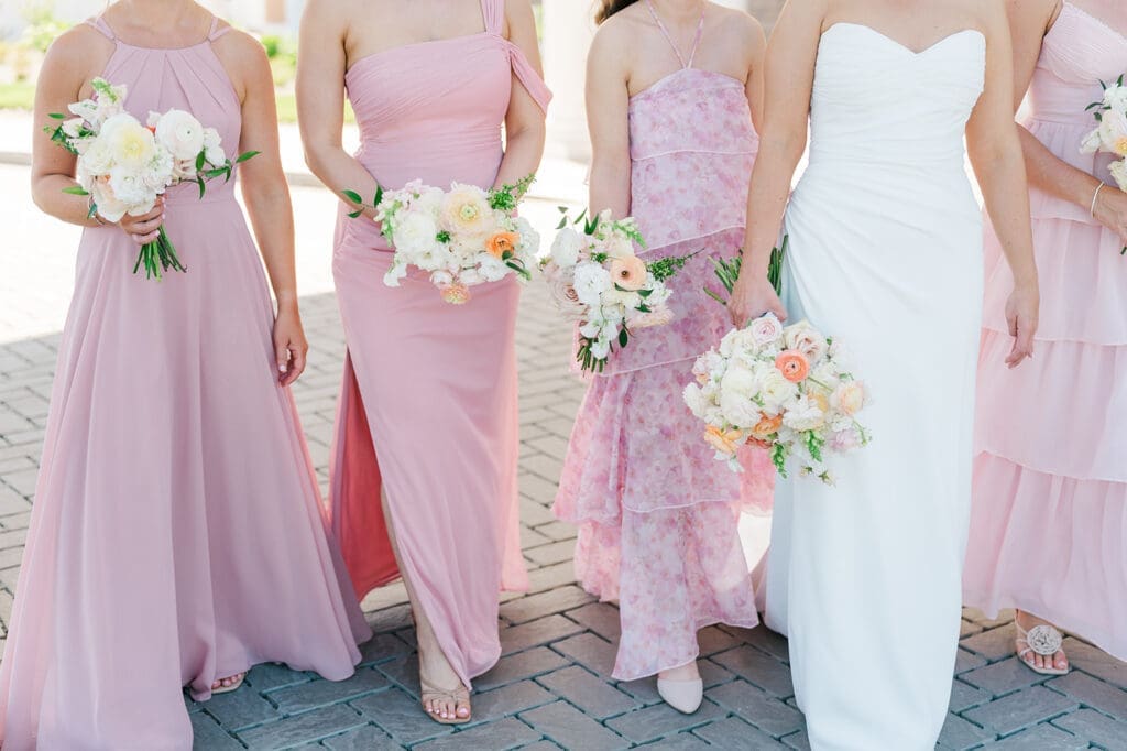 The bridesmaids walk as they hold their pink bouquets