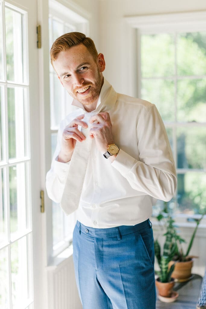Conor puts on his tie and smiles. 