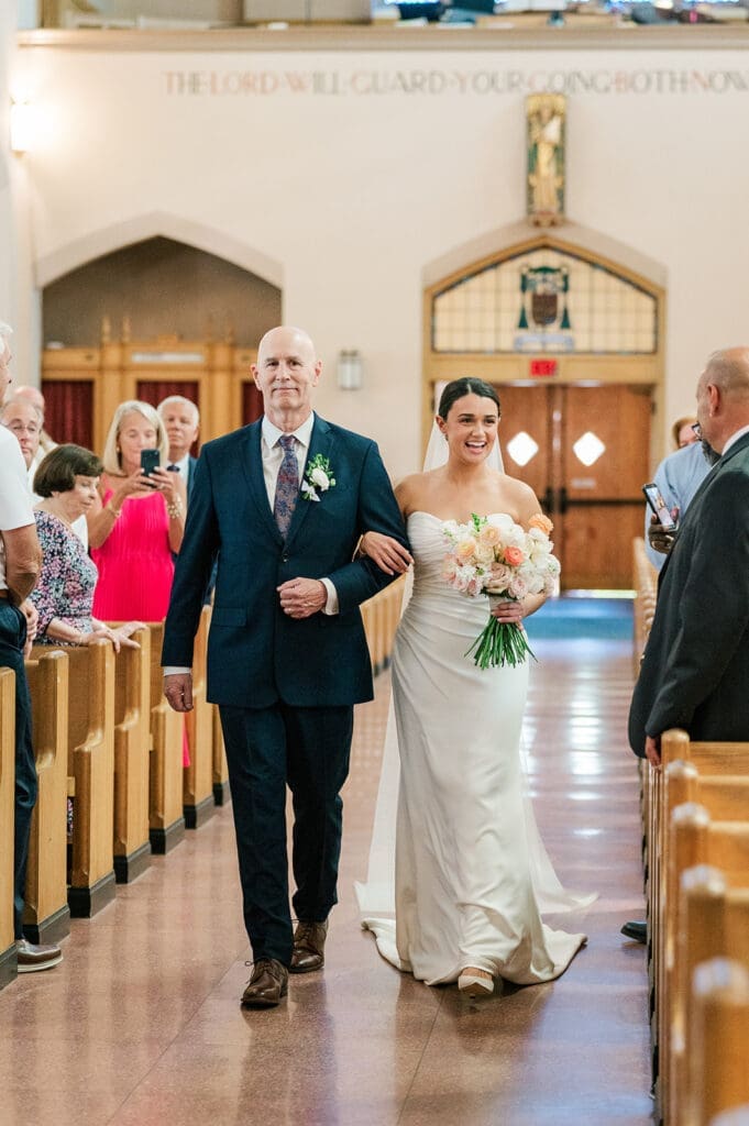 Amy smiles with her dad as they walk down the aisle