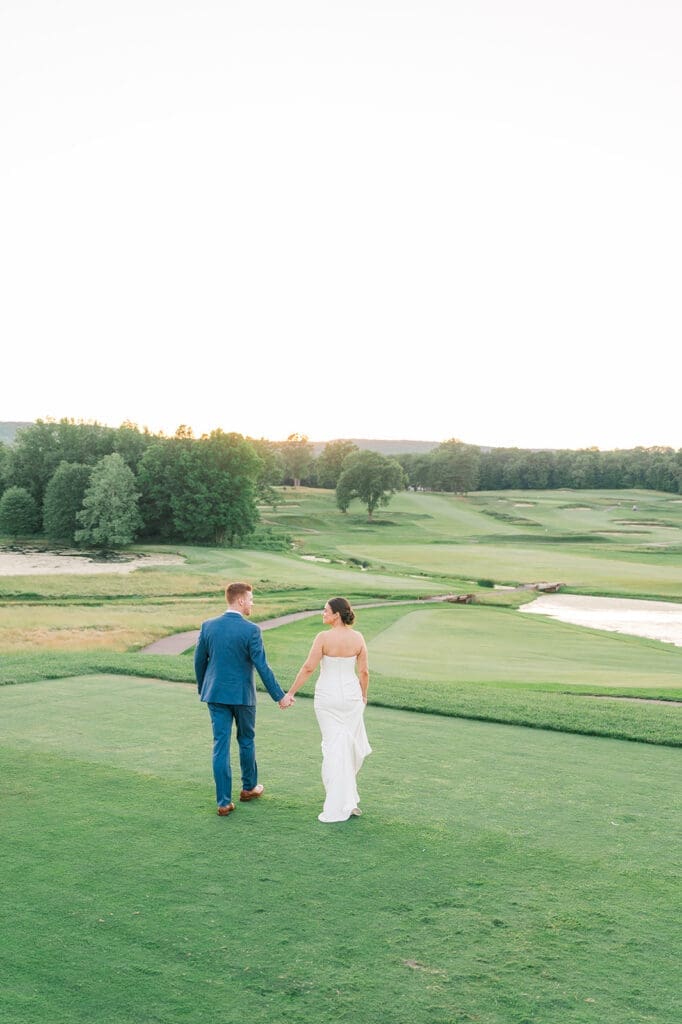 Amy and Conor walk on the golf course as the hills roll behind them. 