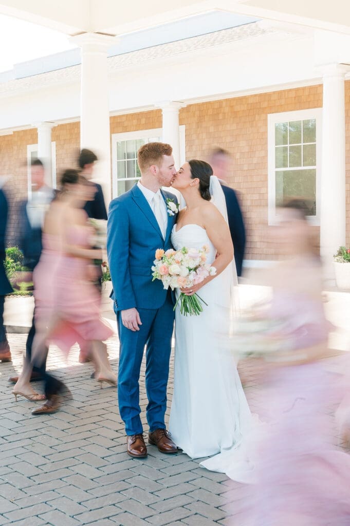the bridal party walks by motion blurred as Amy and Conor kiss for their Wampanoag Country Club Wedding.