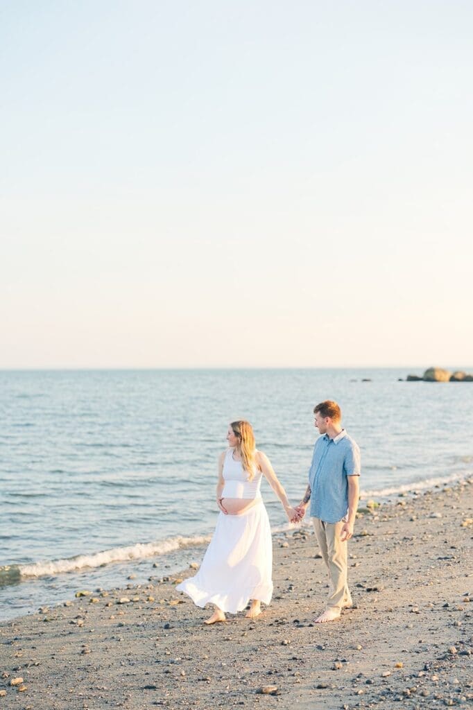 Rich and Lindsey walk alongside the beach as they smile together.
