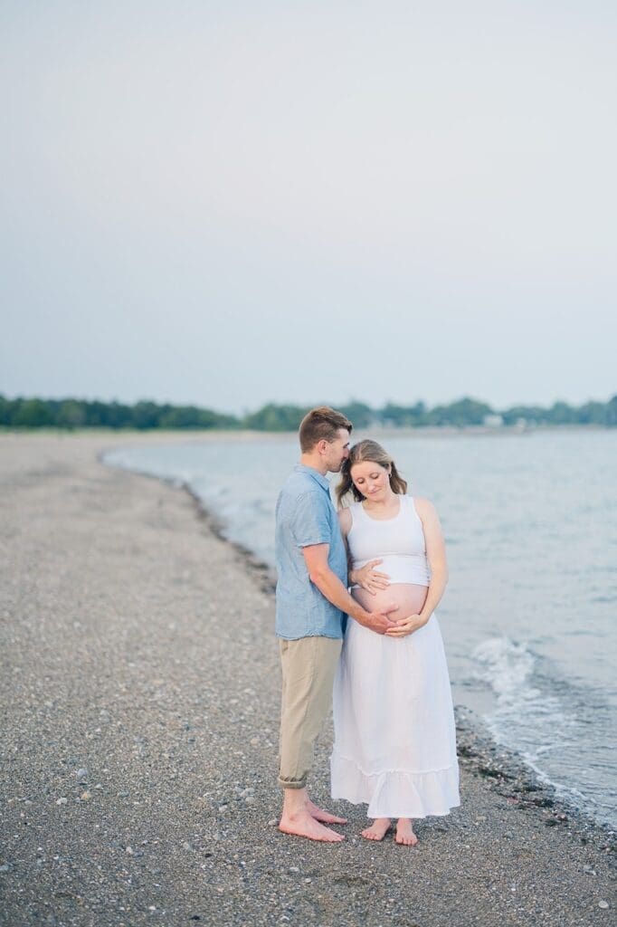 Lindsey holds her belly while Rich kisses the top of her head.