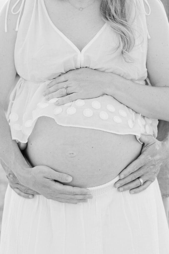 A woman holding her hands on her pregnant belly for her maternity photoshoot in CT.
