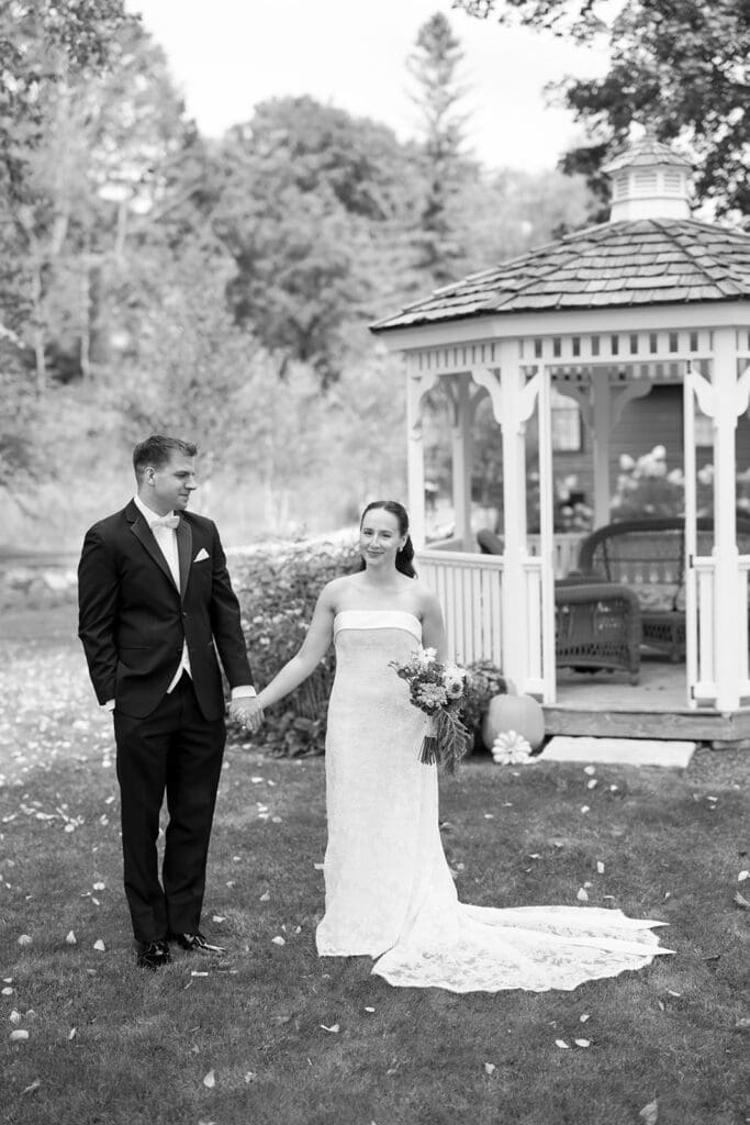A bride and groom hold hands and smile together softly at their Barnstead Inn wedding. 