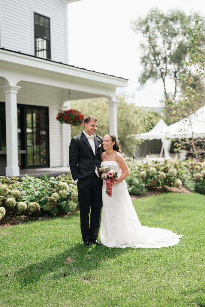 The bride and groom laugh together outside of the Barnstead Inn. 