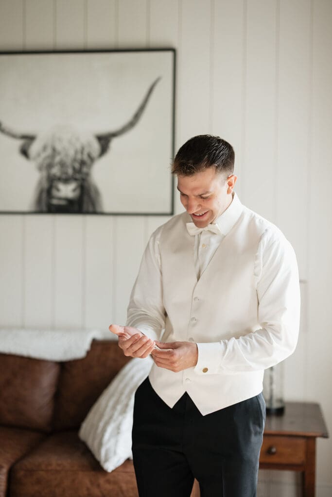 A groom smiles as he adjusts his cufflinks. 