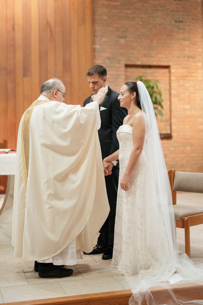 A Catholic priest blesses the bride and groom during their wedding ceremony. 