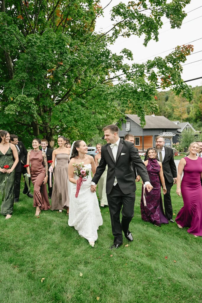 A bride and groom walk alongside their wedding party at the Barnstead Inn. 