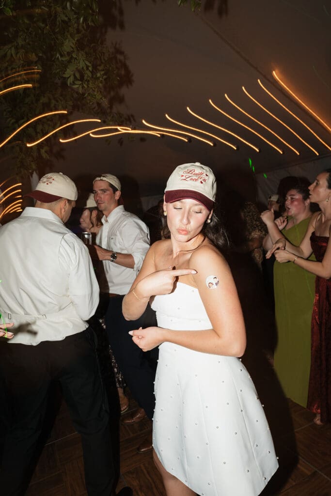 The bride points to a sticker on her shoulder on the dance floor. 