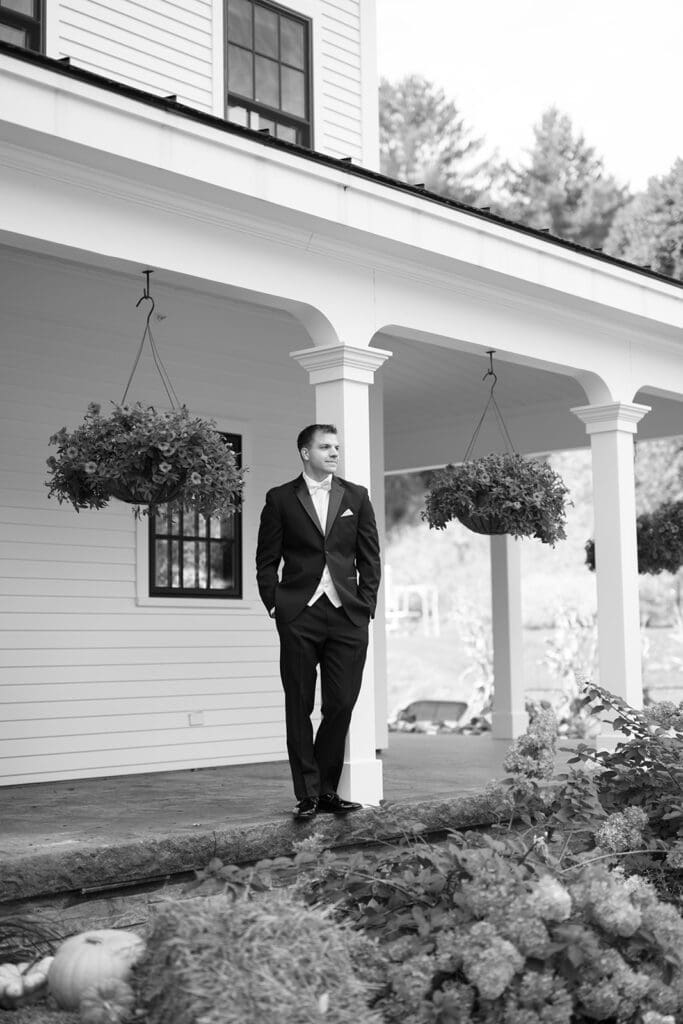 A groom standing on the front porch for his Barnstead Inn wedding. 